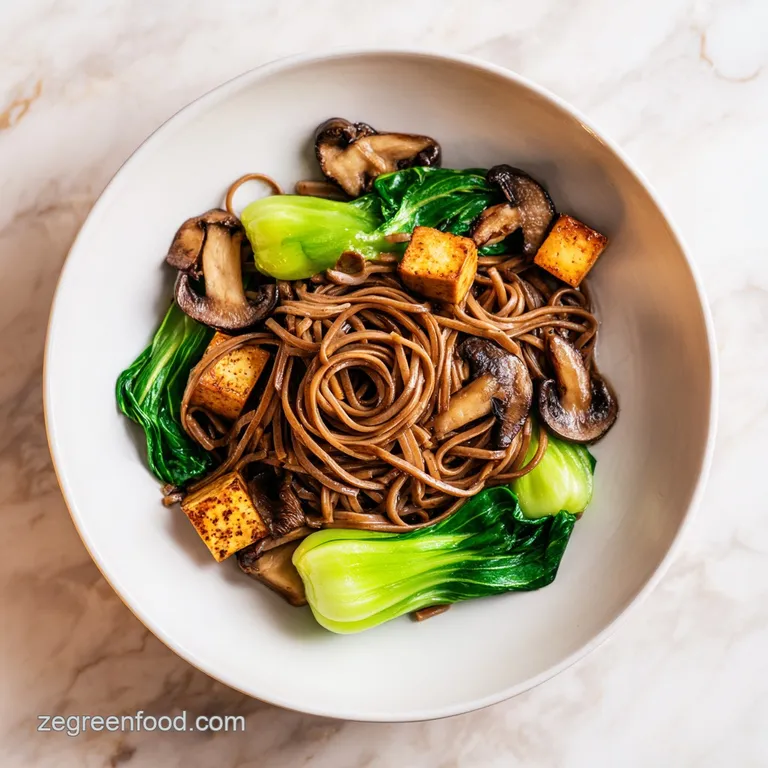 Elegant swirl of dark buckwheat noodles topped with vibrant green bok choy and saut&eacute;ed mushrooms in a blue bowl.